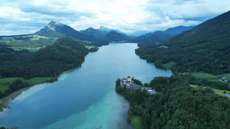 Der türkise Fuschlsee mit Schloss Fuschl auf der bewaldeten Landzunge