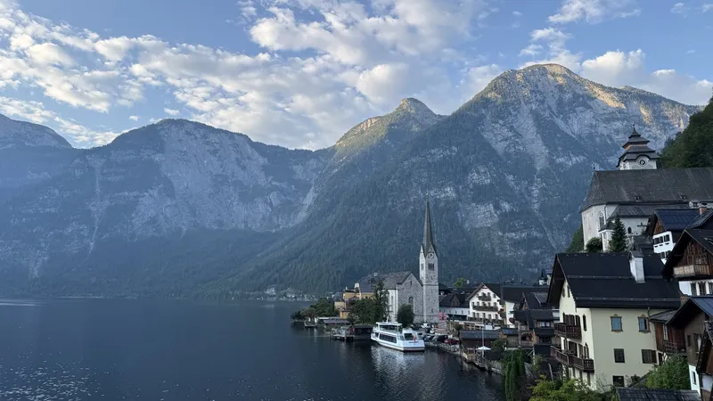 Hallstatt am See mit Kirchturm und Holzhäusern am steilen Ufer, dahinter die Wände des Dachsteins