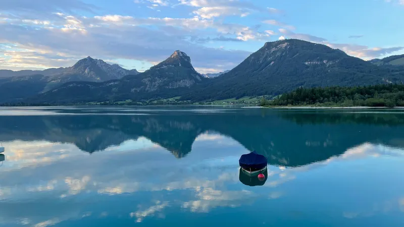 A rowing boat on the mirror-smooth Wolfgangsee, the mountains reflected in the water